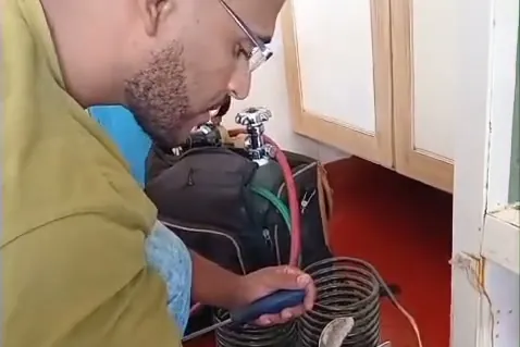 Técnico trabalhando no compressor de uma geladeira na casa do cliente
