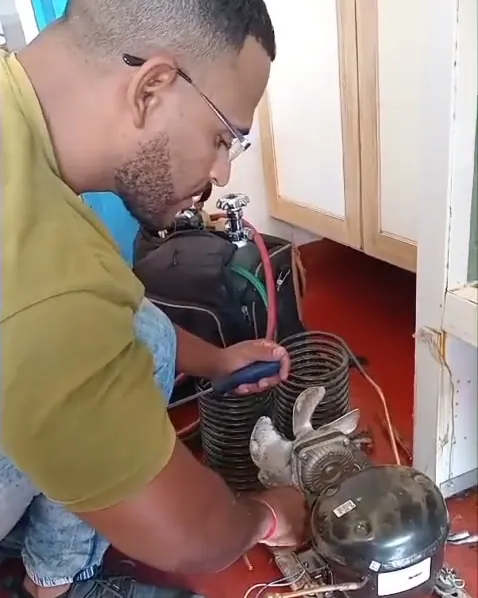 Técnico Gabriel consertando o compressor de uma geladeira